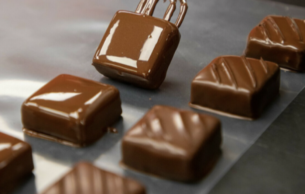 Glossy chocolate squares with ridged tops, one being lifted