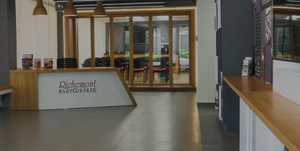 Modern reception area with a wooden desk labeled "Richemont Masterbaker" and glass-walled seating area in the background