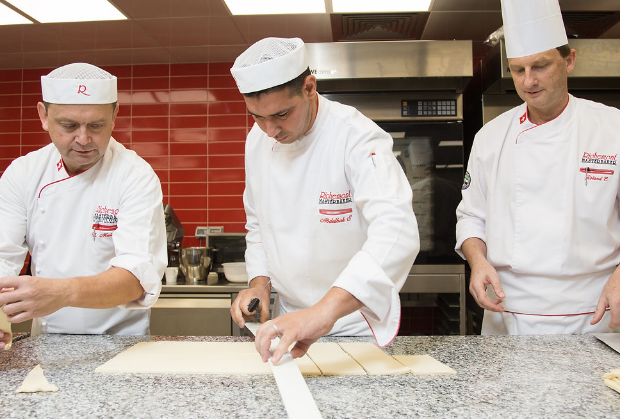Three chefs in a Richemont master baker kitchen preparing pastry dough.