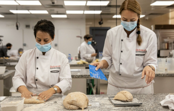 Two chefs in masks preparing dough in a Richemont master baker professional kitchen
