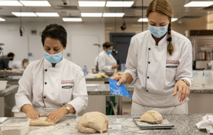 Two chefs in masks preparing dough in a Richemont master baker professional kitchen