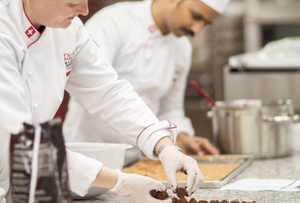 Chefs preparing dishes in a kitchen, focusing on chocolate truffles and other ingredients.
